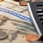 Social Security card on a surface with various denominations of dollar bills and scattered coins, alongside a calculator.