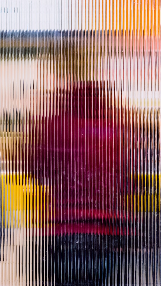 A person with a red shirt is partially visible behind a textured glass panel, creating a blurred effect with vertical lines.