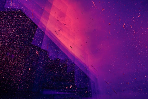 Purple and pink abstract background with scattered particles and a dark silhouette of a building partially reflected.