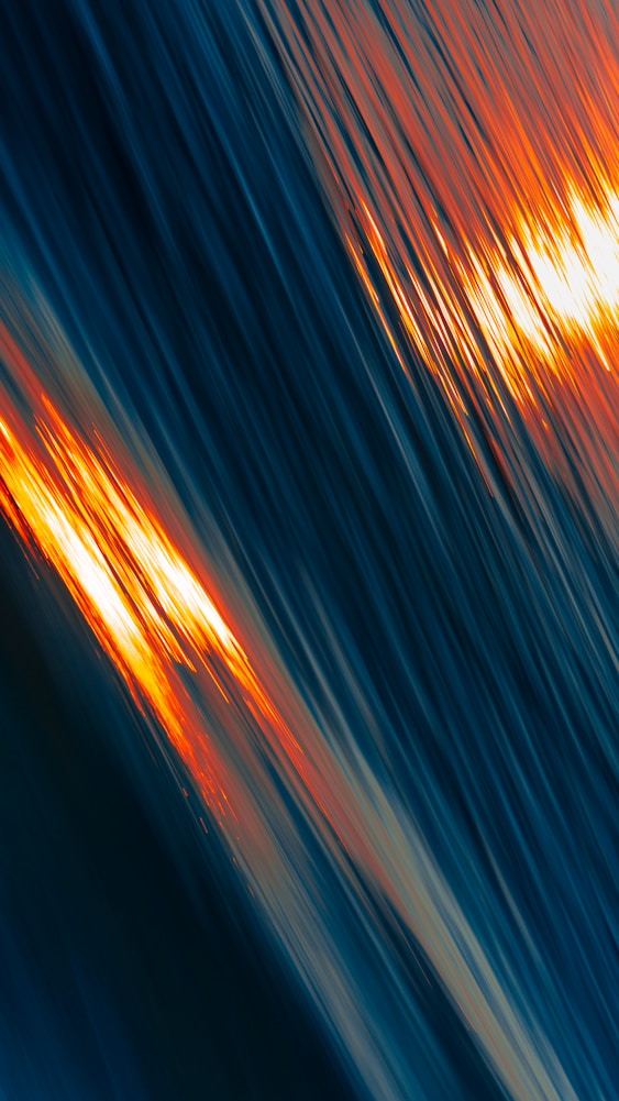Abstract image of blue waves with streaks of orange light reflecting, creating a dynamic, flowing effect.
