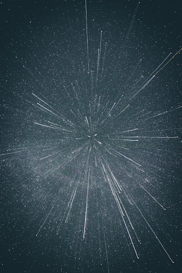 Starry night sky with white streaks radiating outward, creating a sense of depth and motion against a dark background.