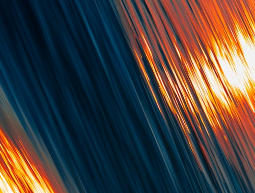 Diagonal streaks of blue and orange create an abstract pattern, resembling light reflections and motion.