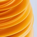 Stacked, wavy layers of bright yellow plastic or rubber, creating a textured spiral pattern against a light background.