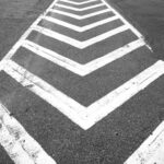 White chevron markings on a dark asphalt surface, creating a zigzag pattern.