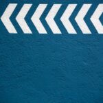 White chevron arrows pointing to the right on a textured blue wall.