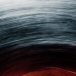 Abstract swirl of colors transitioning from dark gray at the top to vibrant red and orange at the bottom, creating a dynamic effect.