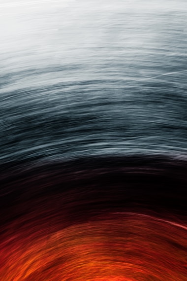 Abstract swirl of colors transitioning from dark gray at the top to vibrant red and orange at the bottom, creating a dynamic effect.