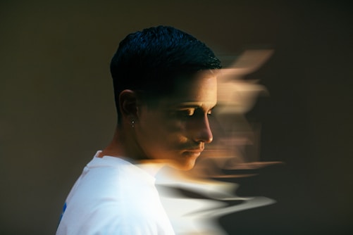 Profile of a person with short dark hair, wearing a white shirt, blurred motion effect creates a sense of movement in the background.
