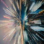 City skyline with a zoom-effect, featuring blurred lights and buildings in vibrant colors, creating a dynamic, energetic scene.