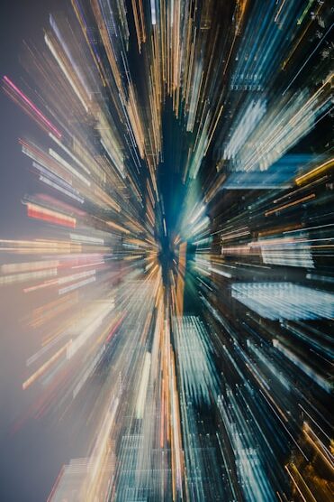 City skyline with a zoom-effect, featuring blurred lights and buildings in vibrant colors, creating a dynamic, energetic scene.