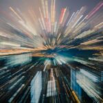 City skyline at night with a zoom effect, showcasing bright lights and blurred buildings in various colors.