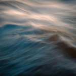 Waves of blue water with soft, flowing patterns and hints of light reflecting off the surface.