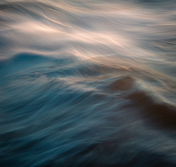 Waves of blue water with soft, flowing patterns and hints of light reflecting off the surface.